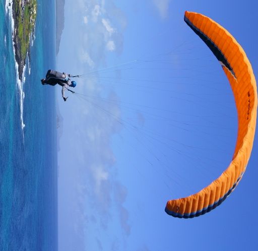 A person paragliding over cliffs near the sea