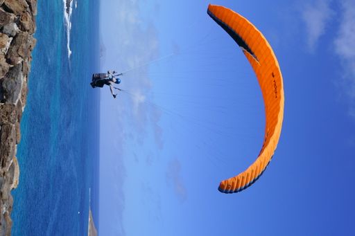 A person paragliding over cliffs near the sea