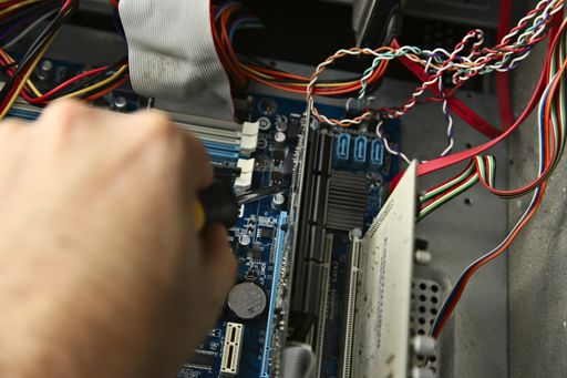A computer technician repairing a motherboard inside a desktop computer in a workshop. This image has selective focus.