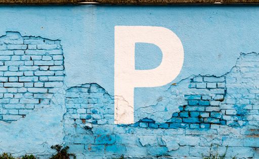 A closeup shot of a white parking sign on a blue destroyed brick wall