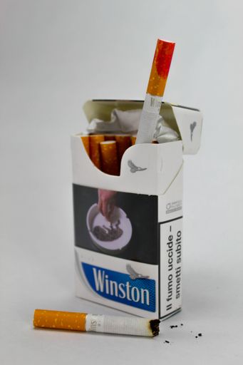 A closeup of a pack of Winston cigarettes with a red lipstick stain against the white background