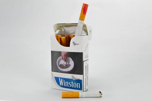 A closeup of a pack of Winston cigarettes with a red lipstick stain against the white background