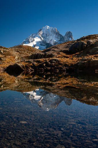 A vertical shot of the Aiguille Verte from Mont Blanc massif reflecting on the water in Chamonix, France