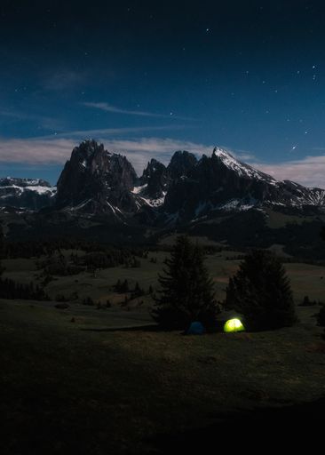 A vertical shot of tents in Seiser Alm near the Langkofel Group mountains in the night in Italy