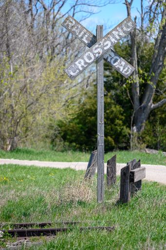 A wooden railroad crossing sign on a summer day
