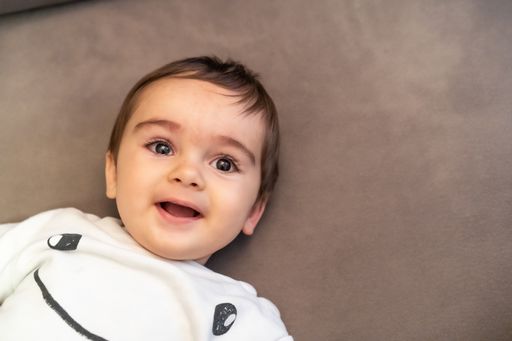 A smiling Caucasian baby lying on the sofa at home