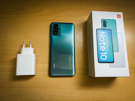 A top view of a Xiaomi - Redmi Note 10 - lake green phone with a box and a charger