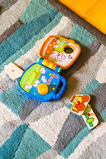A vertical shot of a colorful Fisher Price sound book on a carpet