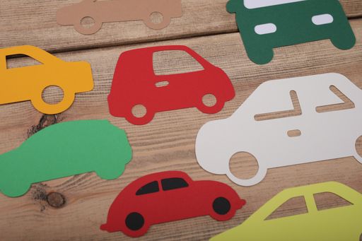A high angle closeup shot of different colored vehicle icons on a wooden background