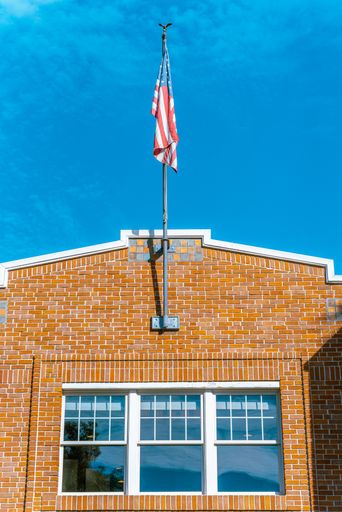 A vertical shot of an American Flag blowing on a brick wall building