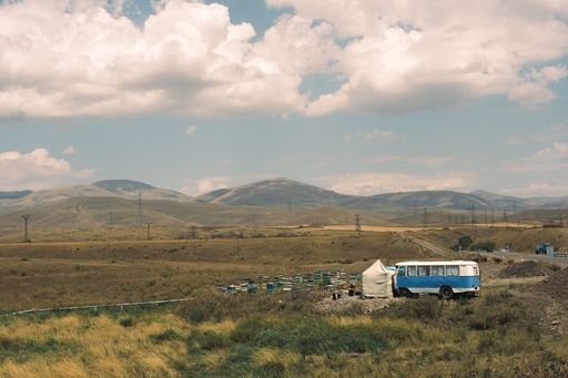 A scenic view of beehives in a rural area on a mountainous background