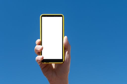 A closeup shot of a man holding his phone vertically in the background of heaven