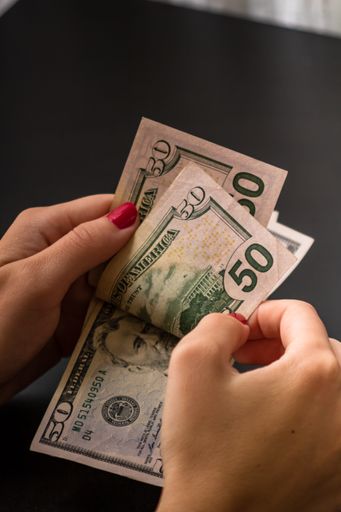 A vertical shot of the detail of USD banknotes. Counting or giving United States Dollars banknotes