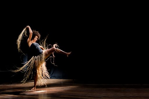 A portrait of a woman dancing on stage against a black background. Salvador, Bahia, Brazil.