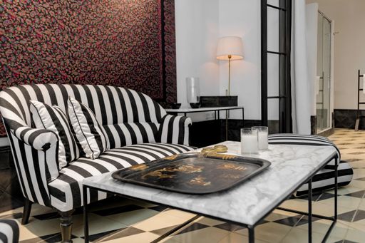 A small living room with an eclectic style with a sofa coffee table and background lamp.