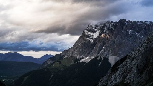 A wide shot of high mountains under cloudy sky