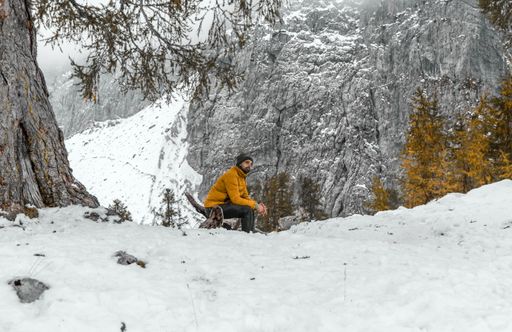 A Male hiker sitting under the tree in snowy misty mountains in the Julian Alps in Slovenia