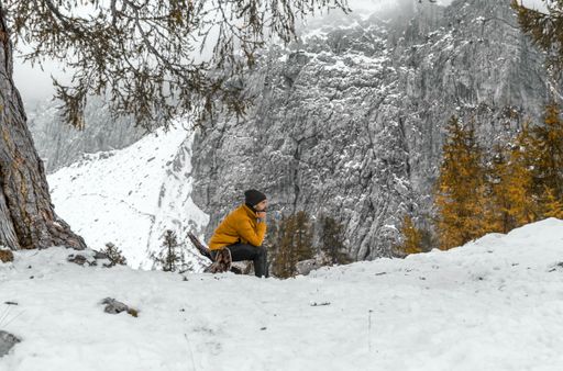 A Male hiker sitting under the tree in snowy misty mountains in the Julian Alps in Slovenia