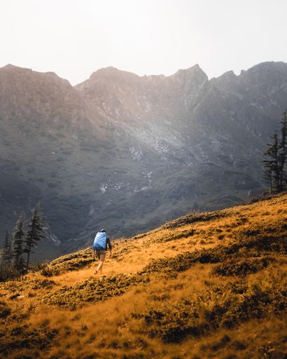 A vertical shot of a man walking over scenic fields on a sunny day