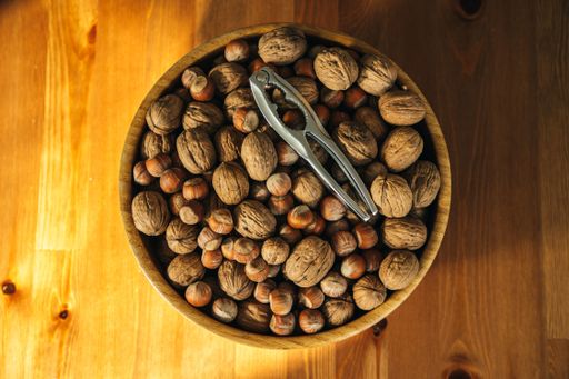 A closeup overhead shot of nuts with a nutcracker in a wooden plate on a wooden table