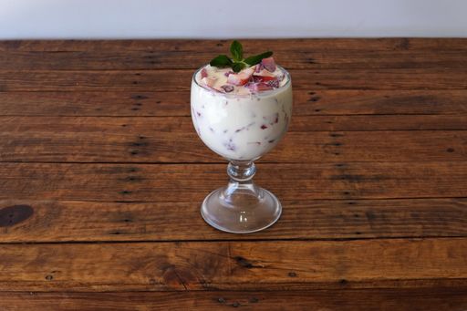 A glass of a vanilla ice cream with fresh strawberries on a wooden table