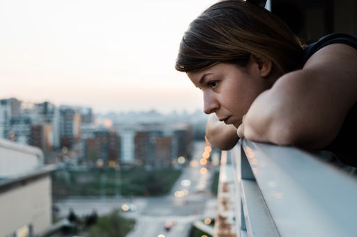 A thoughtful young Caucasian woman looking outside from her apartment balcony in Belgrade, Serbia