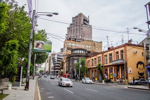 A beautiful view of an urban empty street with a car, trees and buildings in Yerevan, Armenia