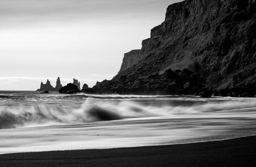 A beautiful view of sea waves touching the beach near the rocky hill
