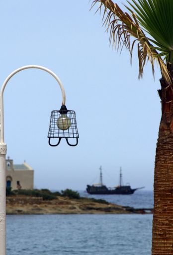 A vertical shot of a lamp by a pine tree near the ocean captured in Crete, Greece