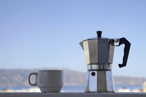 A selective focus shot of a cup and a kettle on a balcony with the sky in the background in Crete, Greece