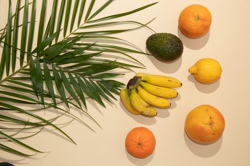 A top view of summer tropical layout made with fresh fruit and green palm leaves on pastel background - Minimal natural flat lay