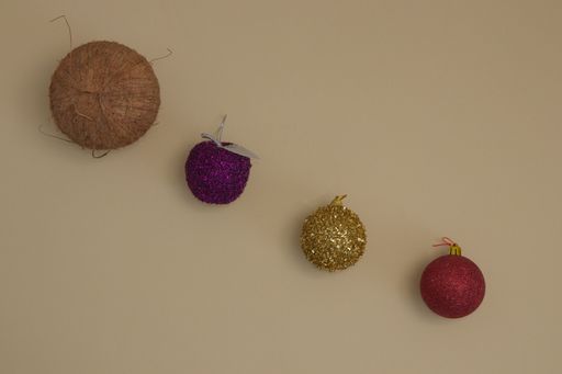 A top view of coconut and Christmas decorations in various colors on a beige background - Minimal flat lay