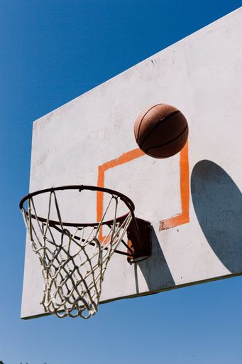 A basketball shot on a hoop against a clear blue sky
