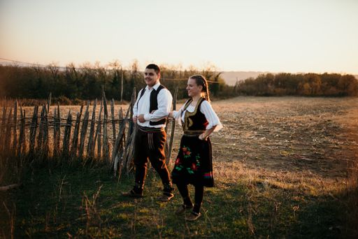 A young couple in Serbian traditional costumes at sunset