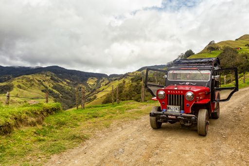 The Landscape view of a red jeep used for tours with the doors open in the mountains outside of Salento, Colombia