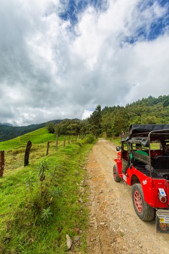 A red jeep parked near pastures in the mountains outside of Salento, Colombia