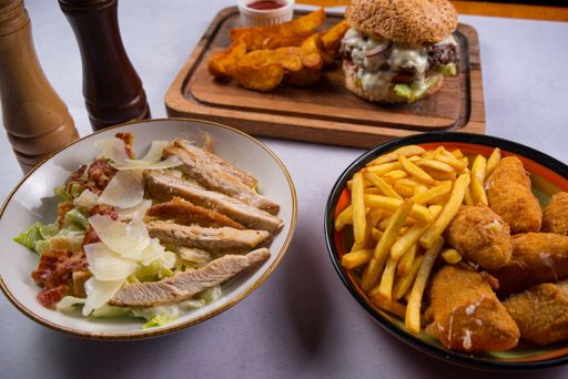 A delicious meal with a hamburger, salad, potato fries and nuggets