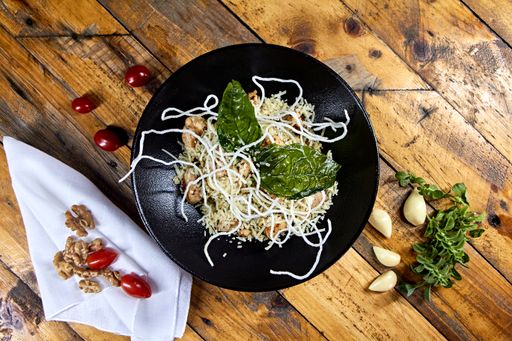 A top view shot of pasta with chicken made of rice noodles on a black plate