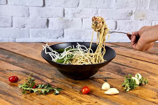 A selective focus shot of pasta with chicken made of rice noodles on a black plate