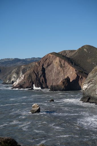 A vertical shot of the sea and rocky cliffs