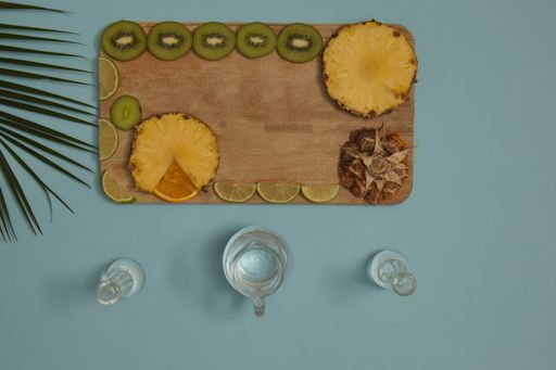 A top view of two glasses and tropical fruits on wood with light blue background