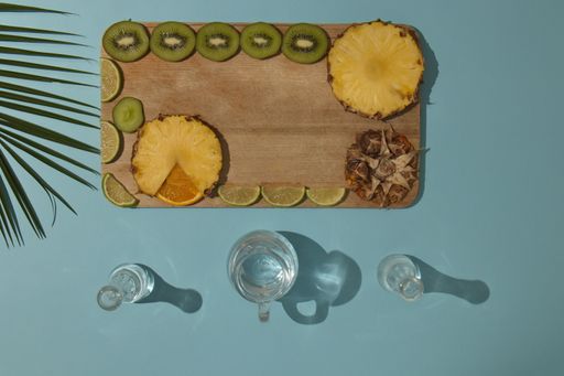 A top view of two glasses and tropical fruits on wood with light blue background