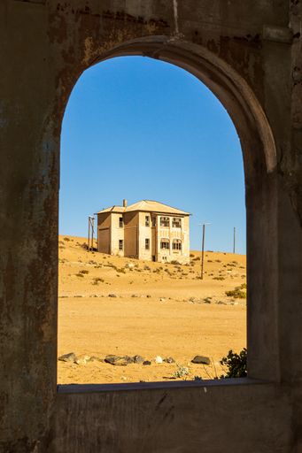 A vertical shot of an old building arch with desert village house view