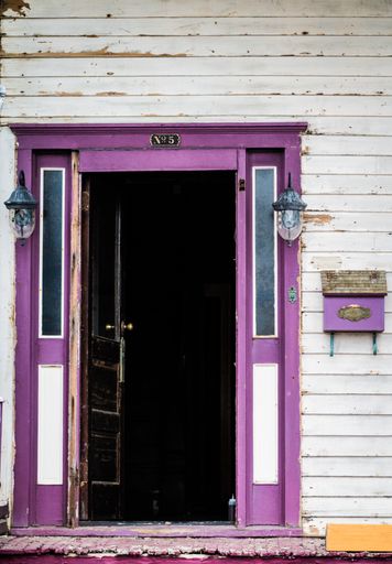 A vertical shot of a purple door on a wooden building