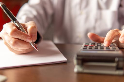 Woman writing and using a calculator,  businesswoman or student. Working from home concept, copy space