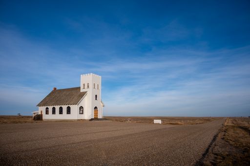 A view of a wooden church against a blue sky in the ghost town of Retlaw, Alberta, Canada.