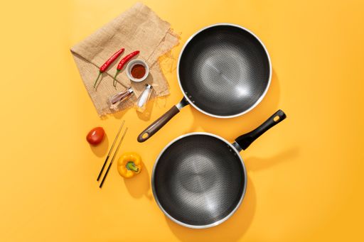 A flat lay of a frying pans with cooking ingredients on the table