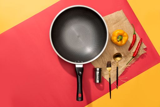 A flat lay of a frying pan with cooking ingredients on the table