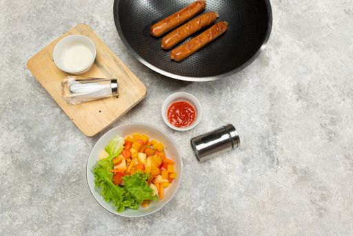 A high-angle shot of a frying pan with cooking spices and already made lunch on the table