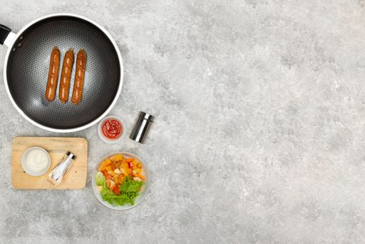 A flat lay of a frying pan with cooking spices and already made lunch on the table